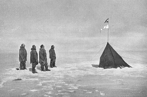 Amundsen and his crew looking at the Norwegian flag at the South Pole