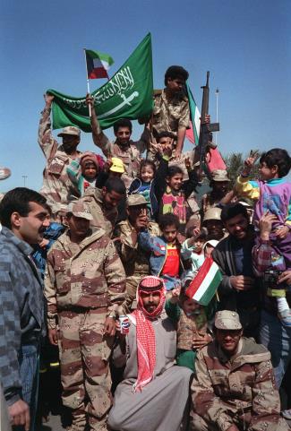 Civilians and coalition forces wave Kuwaiti and Saudi flags as Iraqi forces retreat from Kuwait