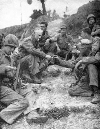 Pyle (center left) sharing a cigarette with a soldier on Okinawa shortly before his death