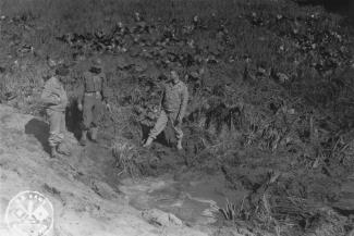 American servicemen inspecting a shell crater after the Japanese attack on Fort Stevens