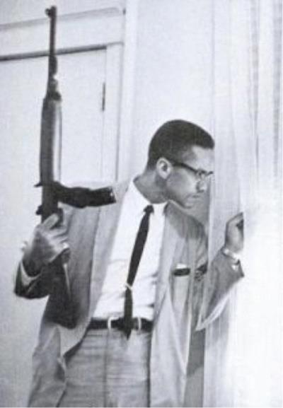 Malcolm X with an M1 Carbine and looking out window